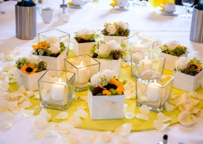 Blumendeko mit Kerzen auf Hochzeitstafel im Jagdschloss Gruenau nahe Ingolstadt. Hochzeitsfotografie in Szene.