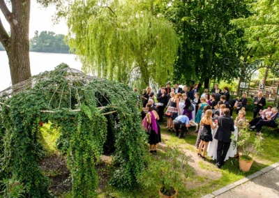 Hochzeitsgesellschaft feiert im Garten am Langwieder See bei München umgeben von Bäumen und Pavillon. Hochzeitsfotografie.
