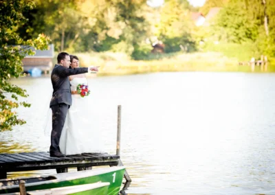 Brautpaar auf Steg am See bei Wessling, Hochzeitsportrait mit blumenhaltender Braut, Hochzeitsfotograf in Starnberg.