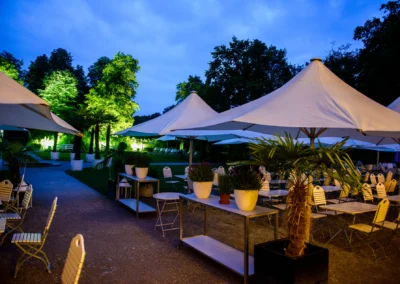 Hochzeitsfoto im Palmenhaus Schloss Nymphenburg, Abendaufnahme der illuminierten Gartenanlage mit Sitzgelegenheiten.