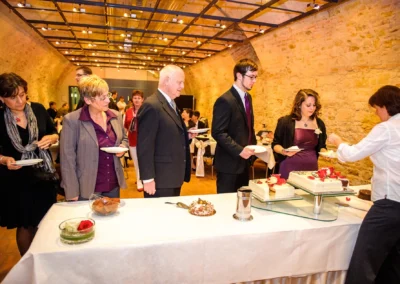 Personen in formeller Kleidung stehen bei einer Hochzeit in Schloss Höchstädt vor einem Buffet mit Torten.