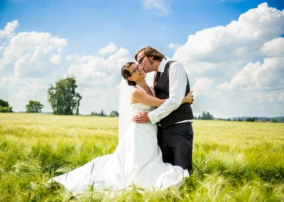 Brautpaar in einem Feld bei Hochzeit nördlich von München, umarmend unter blauem Himmel, Hochzeitsfotografie.