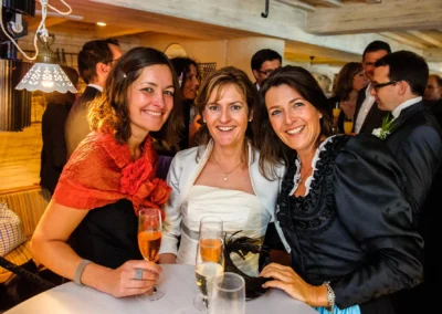 Drei Frauen bei einer Hochzeit am Starnberger See, sie lächeln neben Tischen mit Sektgläsern. Hochzeitsreportage.