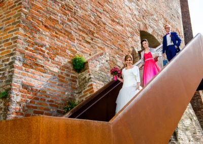 Braut mit Blumenbouquet, begleitet von Gästen, steigt bei der Hochzeit die Treppe in der Burg Trausnitz hinab.