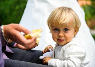 Kleinkind in weissem Pulli bei Hochzeit westlich von Muenchen, aufgenommen von Hochzeitsfotograf.