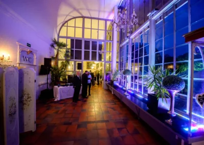 Abendveranstaltung einer Hochzeit im Palmenhaus Schloss Nymphenburg mit festlicher Innenbeleuchtung und Gästen.