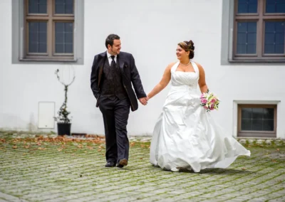 Brautpaar bei Hochzeitsportrait im Schlossumfeld, Hochzeitsfotografie nahe Dillingen, Hand in Hand spazierend.