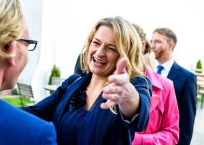 Frau lacht und breitet die Arme aus bei Hochzeit auf Burg Trausnitz. Hochzeitsfoto in lebendiger Stimmung.