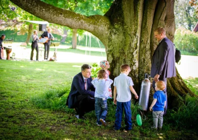 Kinder spielen mit Erwachsenen bei Hochzeit unter einem Baum im Schlosspark von Schloss Aufhausen, nahe Muenchen.