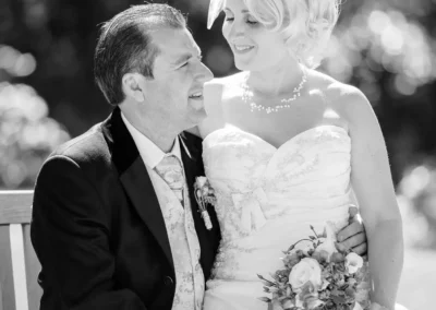 Brautpaar sitzt auf einer Bank im Kurpark Bad Toelz. Hochzeitsportrait mit Blumenstrauss in Schwarz-Weiss.