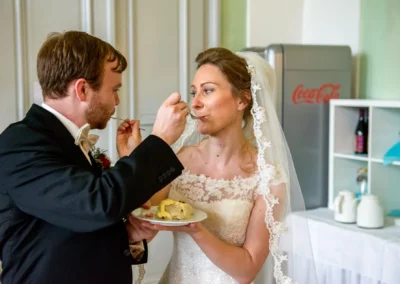 Brautpaar fuettert sich gegenseitig Kuchen bei ihrer Hochzeit in der Orangerie Ansbach. Hochzeitsfotografie Moment.