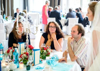 Gäste an Tisch mit Blumenarrangement bei Hochzeitsreportage, westlich von Nürnberg, vom Hochzeitsfotografen aufgenommen.