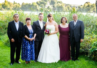 Brautpaar mit Familie bei Hochzeit im Hotel Seehof, Hochzeitfotografie in Wessling, im Hintergrund Natur und See.