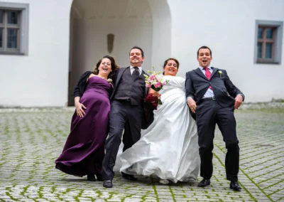 Brautpaar mit Freunden bei Hochzeitsreportage vor Schloss in Hoechstaedt an der Donau, festliche Stimmung und Freude.