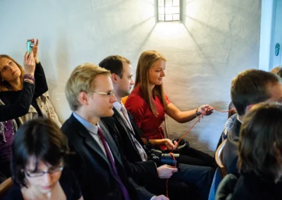 Gäste bei freier Trauung in Schloss Blutenburg. Fokus auf ein Paar und eine Frau beim Fotografieren. Hochzeitsfotografie.