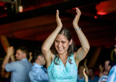 Lachende Frau tanzt auf einer Hochzeitsfeier nahe Rosenheim, umgeben von applaudierenden Gaesten. Hochzeitsfotograf.