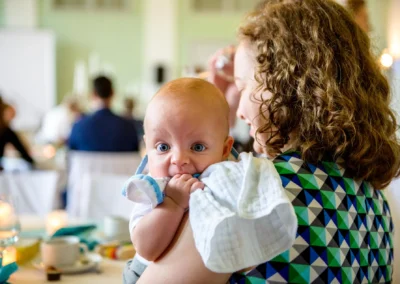 Mutter mit Baby bei Hochzeitsfeier in Orangerie Ansbach, liebevoller Moment dokumentiert durch Hochzeitsfotografie.