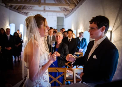 Braut und Bräutigam bei einer freien Trauung in Schloss Blutenburg, München. Hochzeitsfoto mit Gästen im Hintergrund.