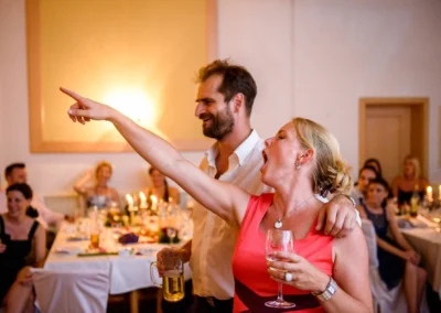 Hochzeitsfeier mit ausgelassenen Gaesten in Roehrmoos, lachende Personen bei Hochzeitsreportage, entspannte Stimmung.