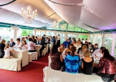 Gäste sitzen festlich in einem Zelt bei einer Hochzeit in Schwabing München und genießen das Hochzeitsessen.