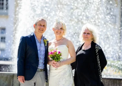 Hochzeitsfoto im Kurhaus Bad Toelz mit Braut, Bräutigam und Gast vor einem Springbrunnen. Oberbayern Hochzeitsreportage.