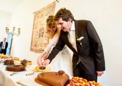 Brautpaar schneidet Hochzeitstorte bei Hochzeitsreportage im Schlosshotel nahe Neuburg an der Donau.