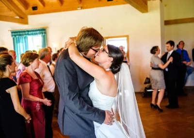 Brautpaar tanzt eng umarmt bei ihrer Hochzeit nördlich von Dachau, umgeben von Gästen in festlicher Stimmung.