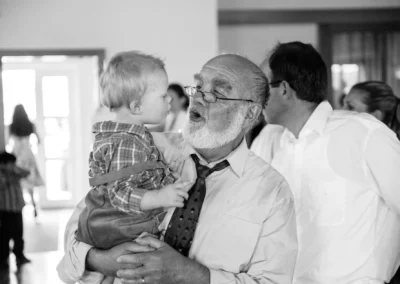 Älterer Herr hält ein Kind bei Hochzeitsfeier nördlich von München, Moment festgehalten von einem Hochzeitsfotografen.