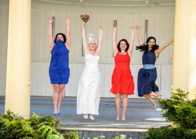 Braut und Brautjungfern springen in bunten Kleidern in Bad Toelz, Hochzeitsfotografie suedlich Muenchen.