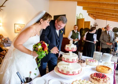 Brautpaar beim Anschneiden der Hochzeitstorte im Brauereigasthof Aying, festgehalten in einer Hochzeitsreportage.