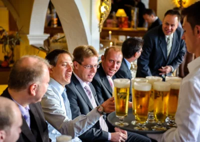 Gäste bei einer Hochzeit am Starnberger See genießen Bier und lachen, festgehalten von Hochzeitsfotograf.