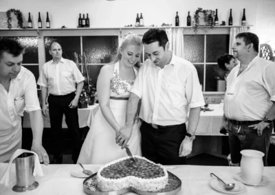 Brautpaar schneidet Herztorte bei Hochzeit in Röhrmoos, umgeben von Gästen. Hochzeitsreportage im Dachauer Hinterland.