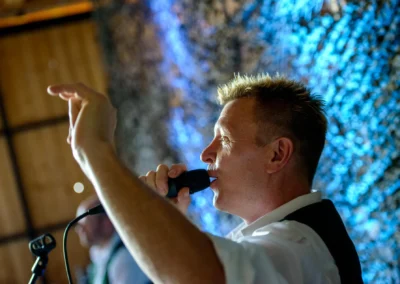 Sänger mit Mikrofon bei Hochzeitsfeier in Trachtenheim Irschenberg, aufgenommen von Hochzeitsfotograf München.