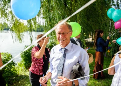 Hochzeitsreportage am Langwieder See bei Muenchen. Gaeste mit Luftballons und Getraenken im Freien feiern.