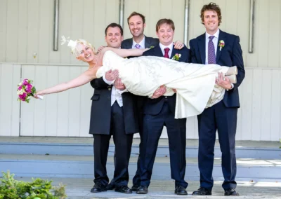Braut in weissem Kleid wird von Trauzeugen getragen, Hochzeitsfoto im Kurhaus Bad Toelz.