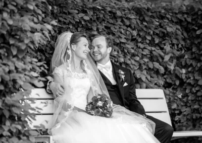 Brautpaar auf einer Bank im Hofgarten Ansbach, laechelnd. Hochzeitsfoto von einem Hochzeitsfotografen.