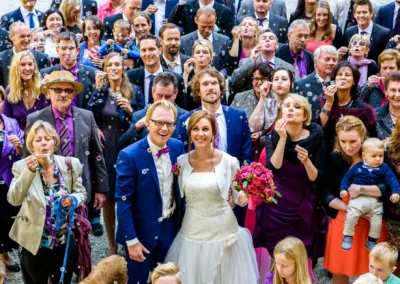 Hochzeitspaar und Gaeste mit Seifenblasen in Landshut. Braut mit Blumenstrauss, festliche Stimmung.