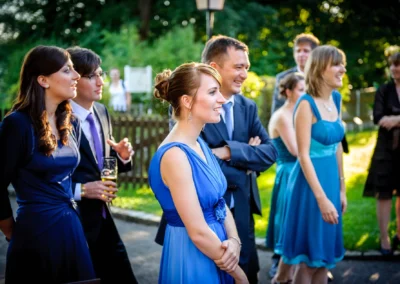 Gruppe von Hochzeitsgaesten in blauer Kleidung laechelt bei einer Hochzeit nahe Ammersee im Freien.