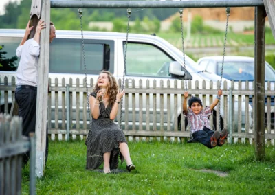 Frau mit Glas lacht, Kind schaukelt bei Hochzeit nördlich von München, aufgenommen vom Hochzeitsfotograf.