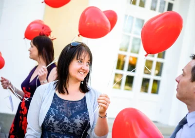 Drei Hochzeitsgaeste mit roten Herzballons im Kurhaus Bad Toelz, aufgenommen bei einer Hochzeitsreportage.