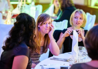 Gäste sitzen lächelnd am Tisch bei einer Hochzeitsfeier in Schwabing München. Hochzeitsfotografie dokumentiert den Moment.
