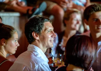 Gruppe von Hochzeitsgaesten lacht und plaudert bei einer Hochzeit nahe Rosenheim. Hochzeitsfotografie im Reportagestil.