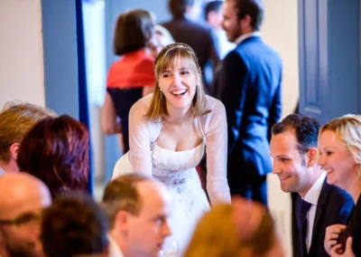 Lachende Braut bei Hochzeit im Schloss Gruenau bei Neuburg an der Donau, umgeben von Gaesten, Hochzeitsreportage.