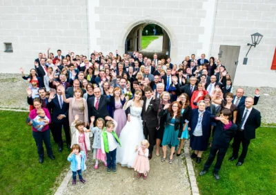 Eine Hochzeitsgesellschaft winkt vor Schloss Grunau, nahe Neuburg an der Donau. Hochzeitsreportage.