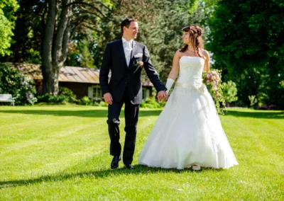 Brautpaar beim Shooting im Garten von Schloss Aufhausen, beim Hochzeitsfoto nahe Muenchen, Hand in Hand spazierend.
