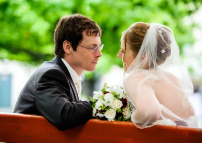 Brautpaar auf einer Bank mit Blumenstrauss bei Hochzeitsreportage im Schloss Blutenburg, Hochzeitsfoto in Muenchen.