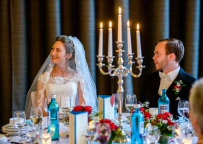 Brautpaar bei Kerzenlicht am Tisch in Ansbach, elegant gekleidet mit Blumenarrangements. Hochzeitsreportage.