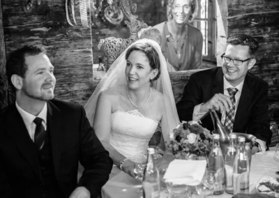 Braut mit Schleier und zwei Gaesten feiert im Brauereigasthof Aying bei der Hochzeitsreportage.