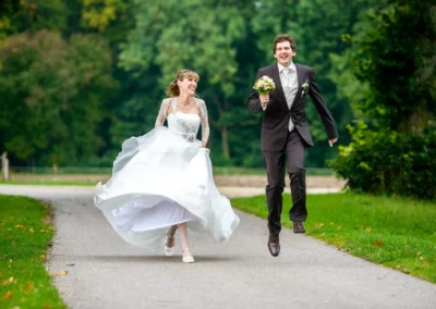 Brautpaar laeuft lachend im Garten von Schloss Gruenau, Hochzeitsreportage nahe Neuburg an der Donau.