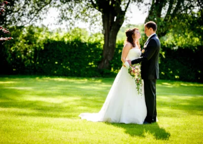 Brautpaar bei Hochzeitsreportage im Park von Schloss Aufhausen nahe Muenchen, romantisches Ambiente mit Blumenstrauss.